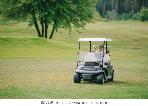 一个女人开着小车，在高尔夫球场夏季日高尔夫球场女子帽骑高尔夫球车